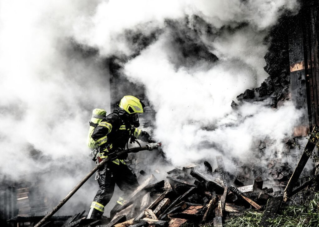 A determined firefighter fights a raging fire amidst thick smoke, highlighting bravery and courage.